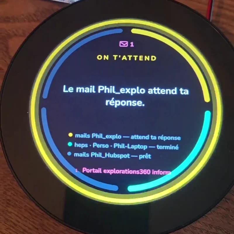L'écran rond de la Vigie en alerte : anneau jaune, mention « On t'attend » et enveloppe avec le chiffre 1. Au centre, « Le mail Phil_explo attend ta réponse », puis la liste des agents et des boîtes mail suivis